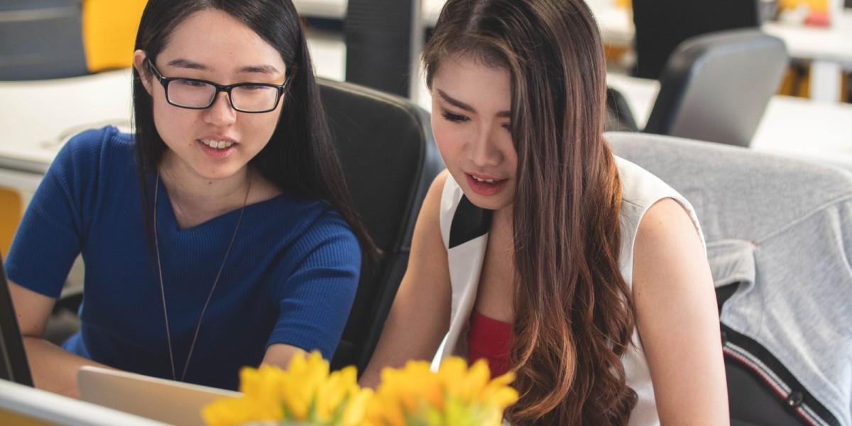 two women discussing content on laptop